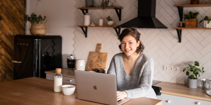 Girl sitting on bar stool in kitchen with laptop