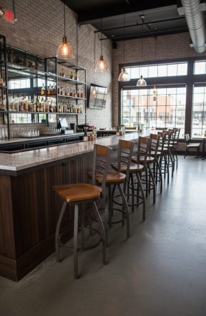 Holland's Eleanor 880 Bronze Metal Swivel Bar Stool with Medium Wood Back and Seat - in Restaurant